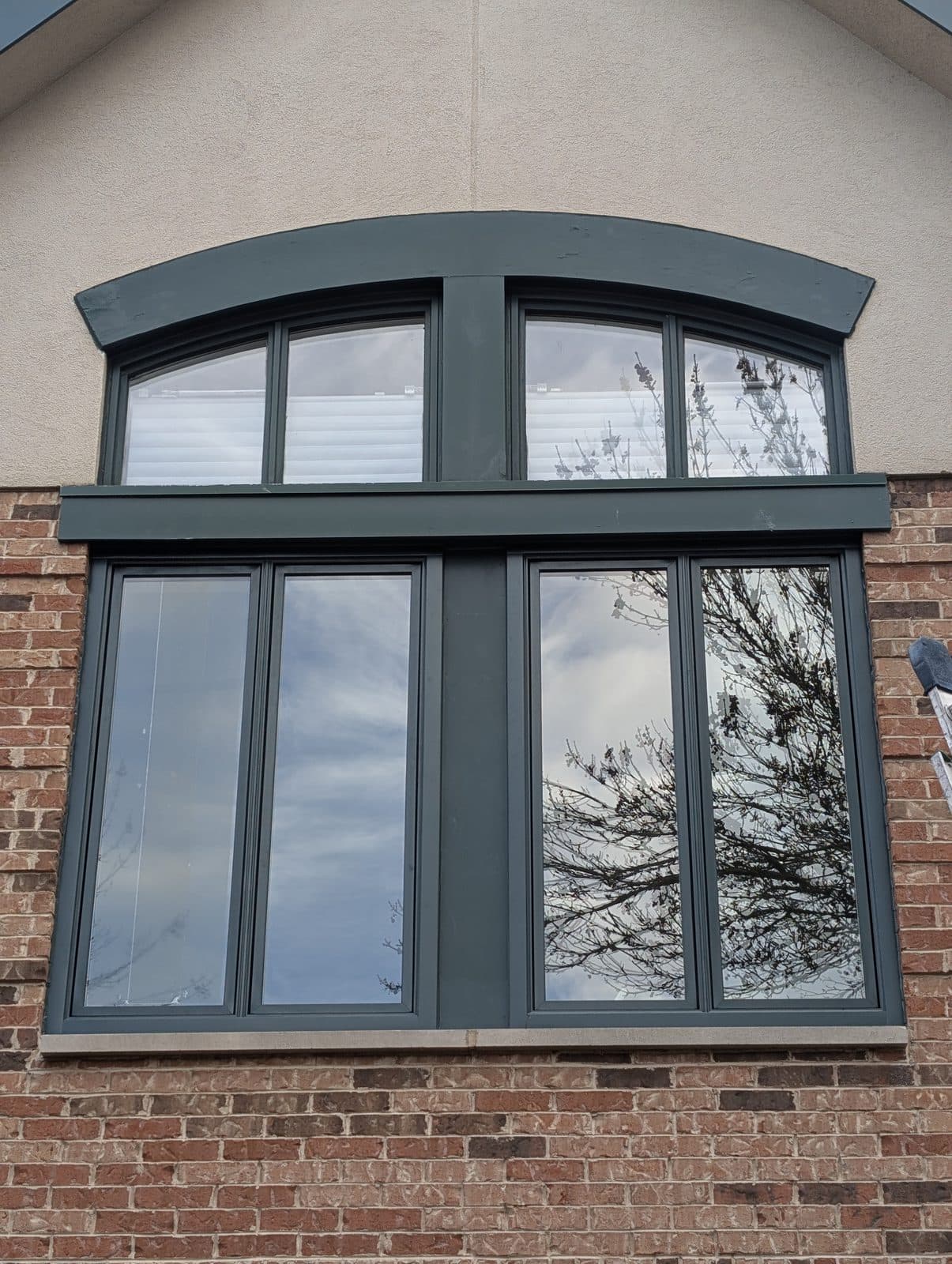 Black-clad casement windows with an arched transom on a brick home in Southeast Wisconsin