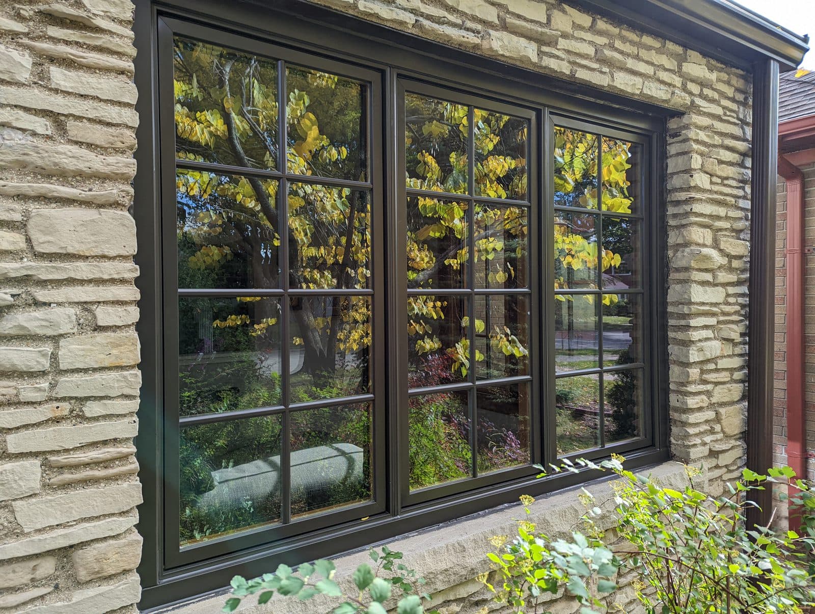 Bronze-clad casement windows with colonial grilles on a stone home in Southeast Wisconsin
