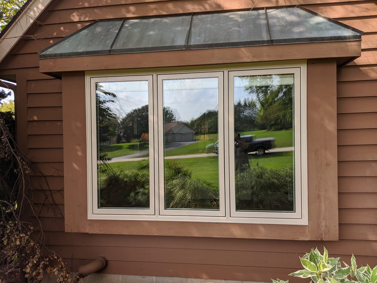 Cream casement windows under a metal bay roof on a Southeast Wisconsin home