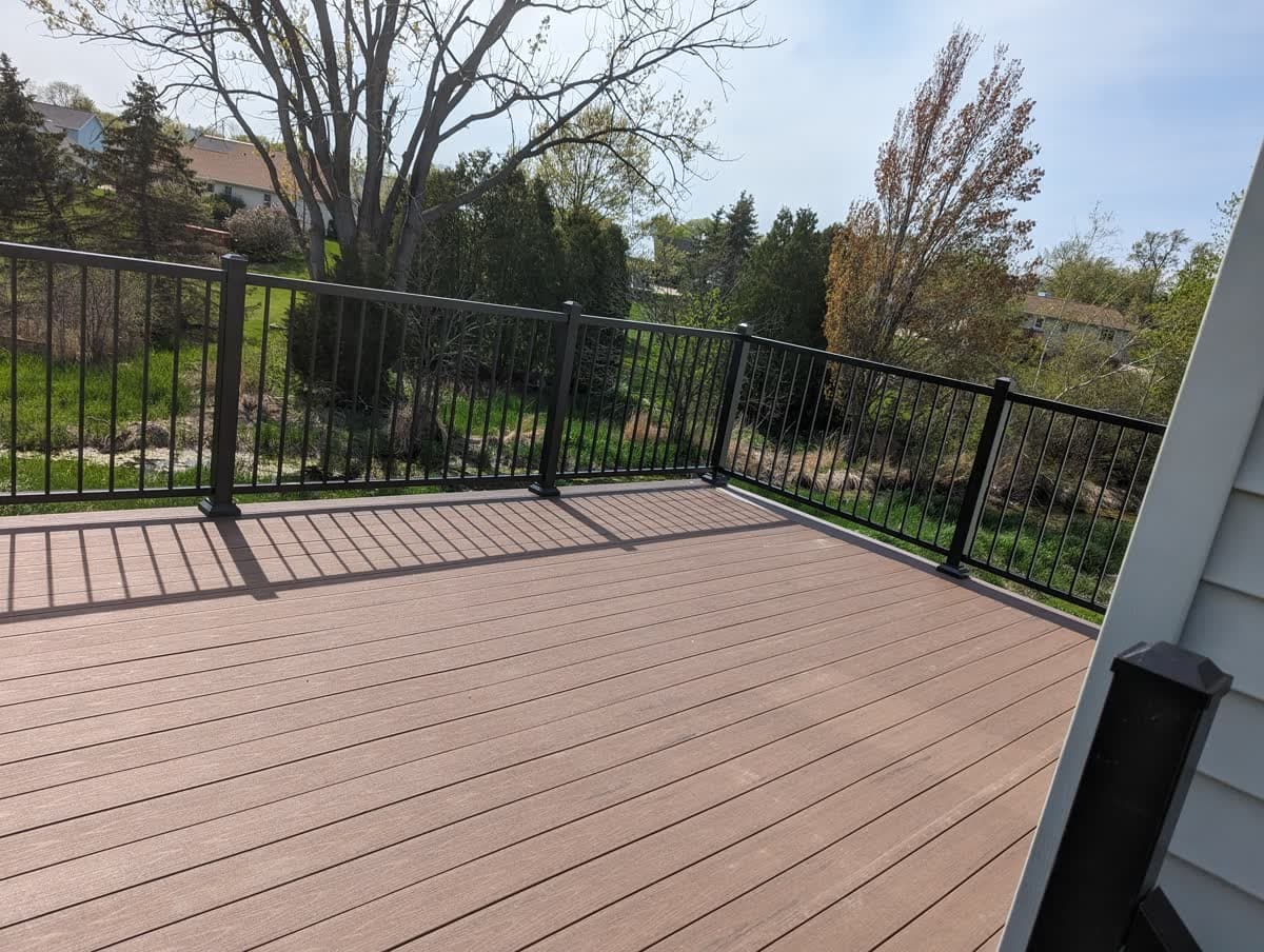 Elevated composite deck with black aluminum railing overlooking a wooded backyard in SE Wisconsin