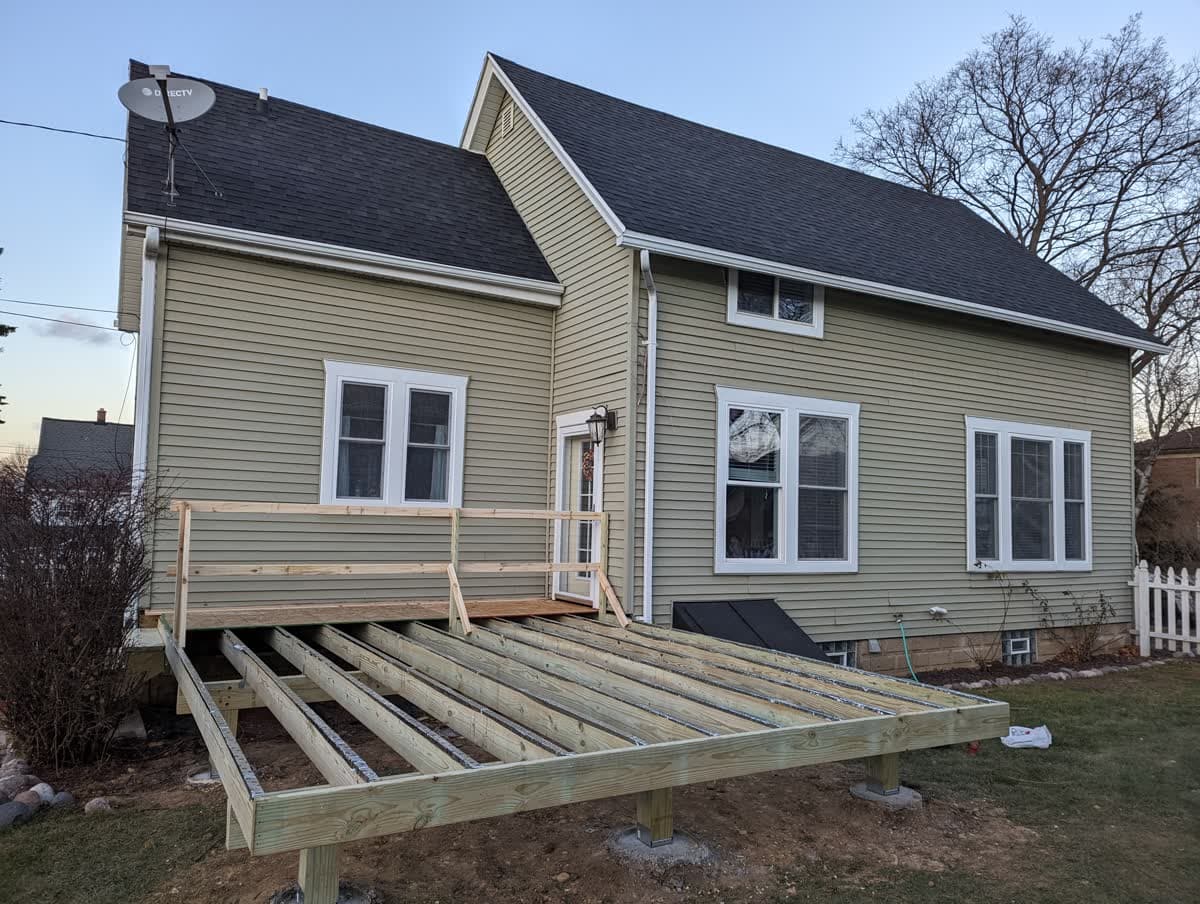 Pressure-treated deck framing on posts and footings during construction in Wisconsin