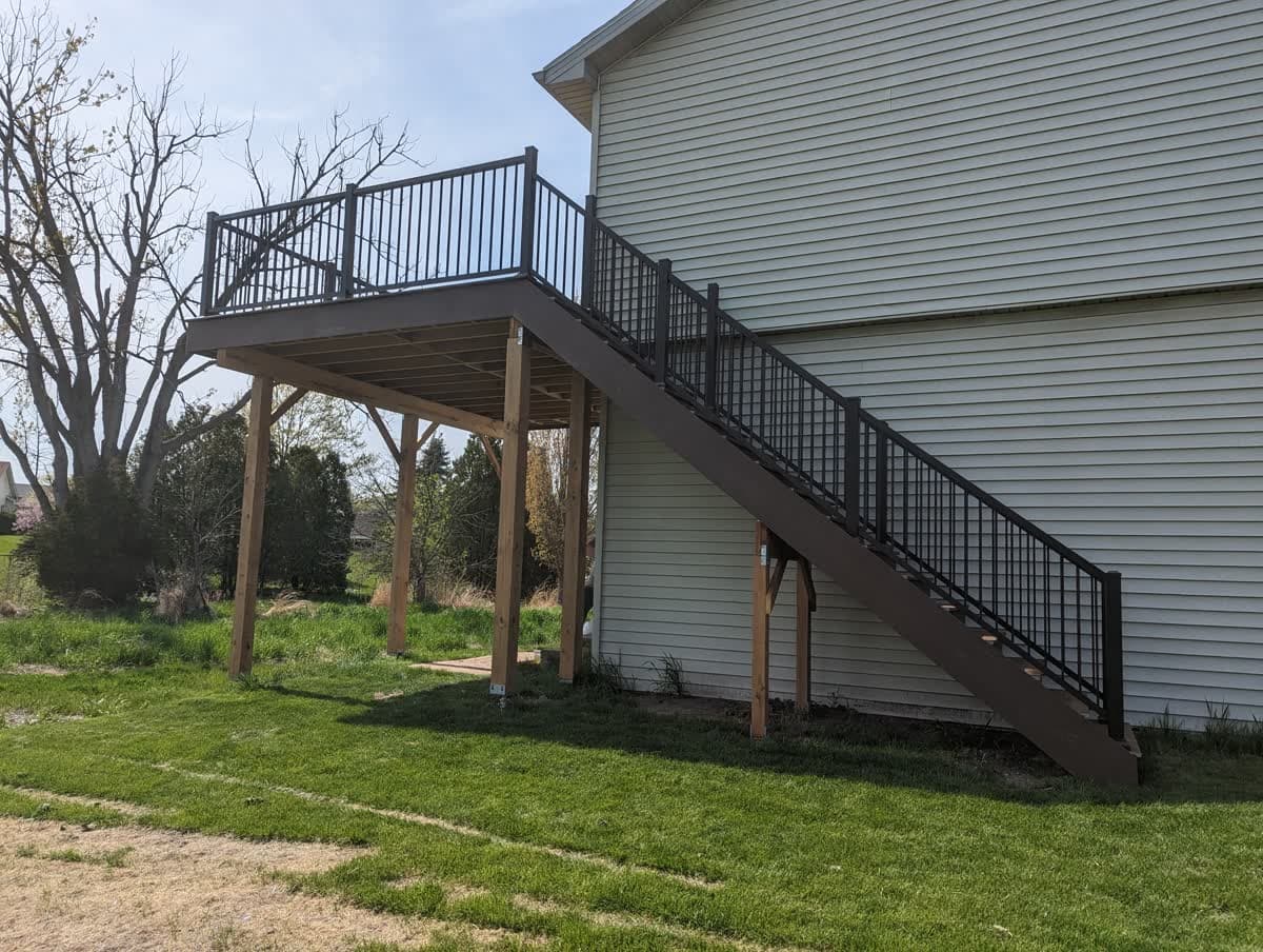 Raised backyard deck with black metal railing and staircase in Southeast Wisconsin